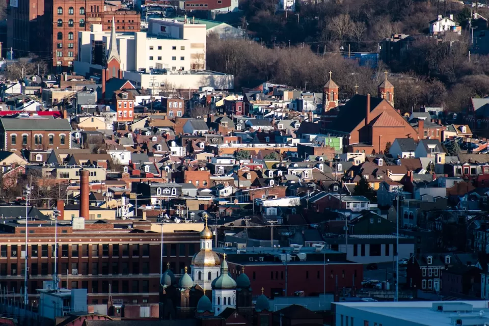 Aerial view of dense South Side Flats neighborhood in Pittsburgh, PA with Orthodox church spires in foreground.